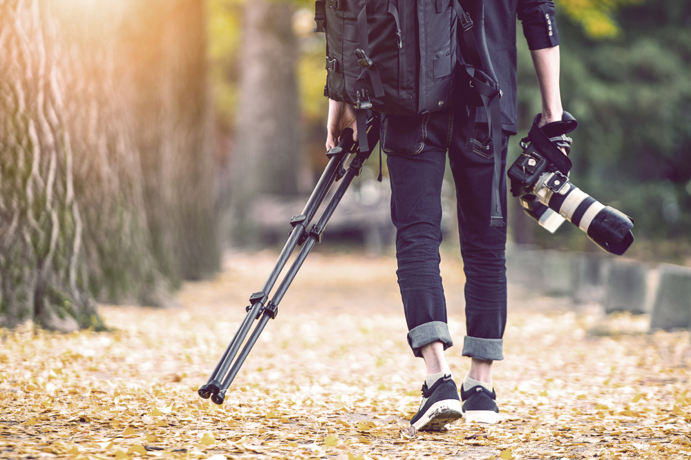 a photographer carrying a camera and tripod