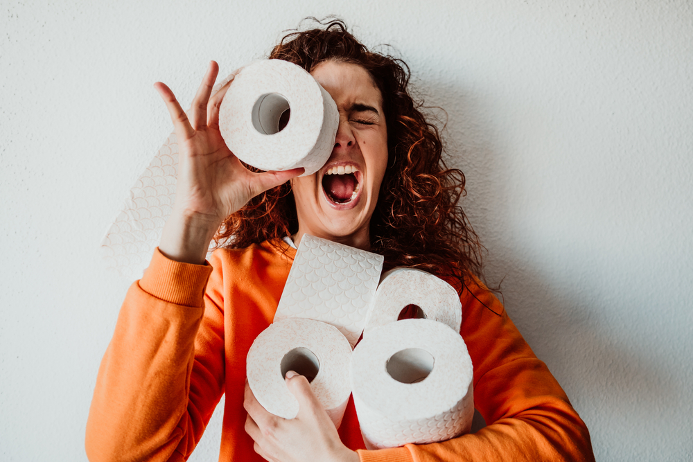 a woman holding an armful of toilet paper