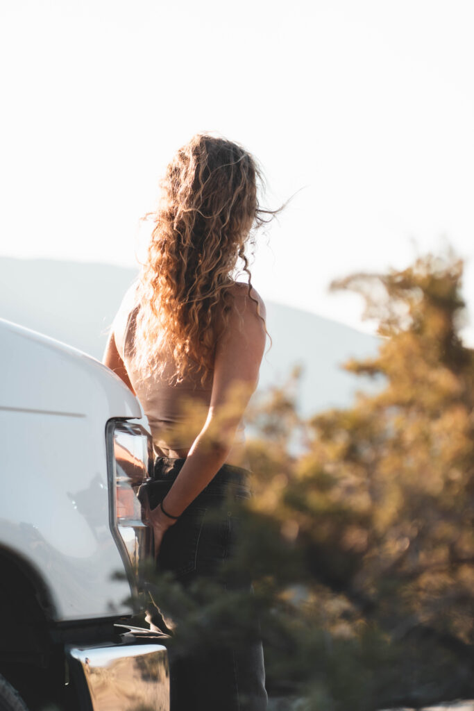 A woman sitting on the front bumper of an RV