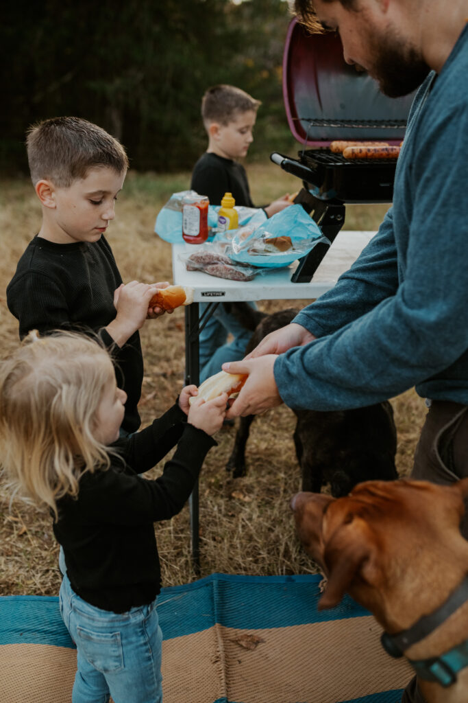 a dad handing kids some food while camping