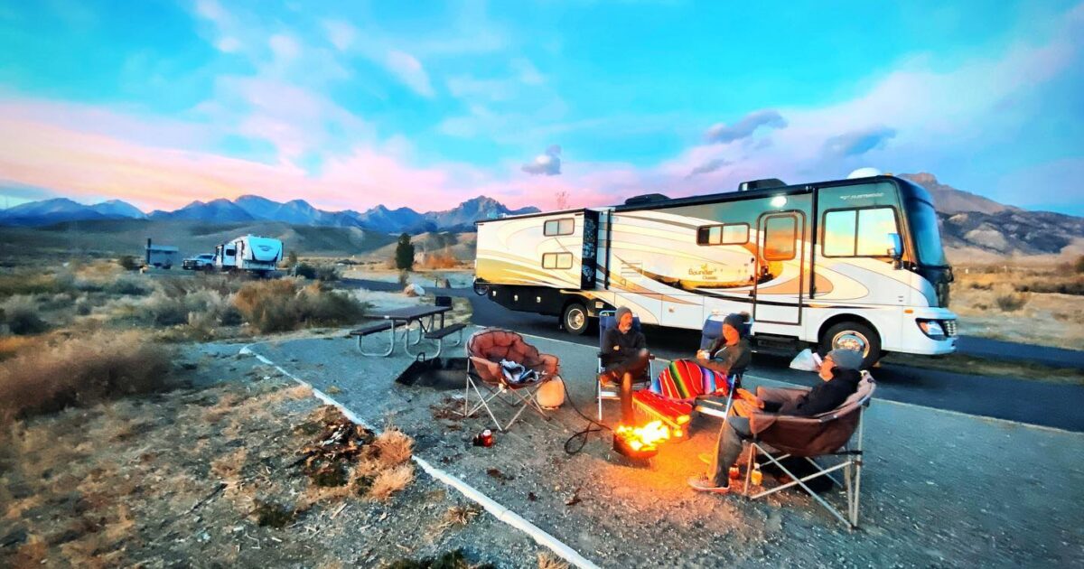 an RV set up with a family relaxing around a campfire