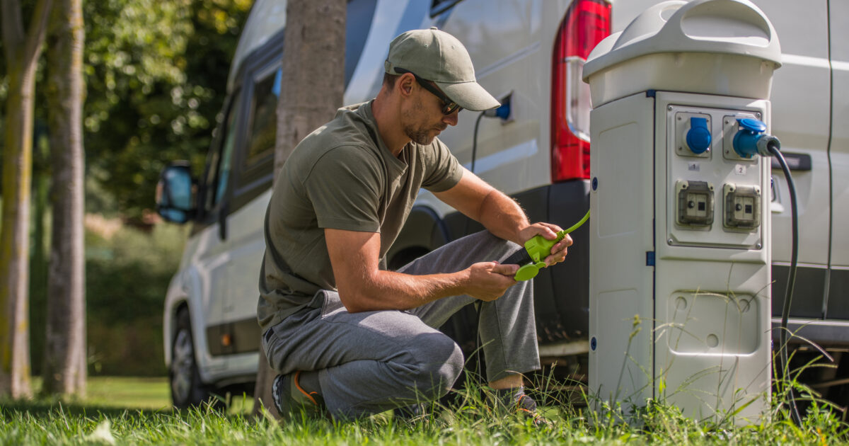 Man Attaching Electric Plug to RV Park Hookup