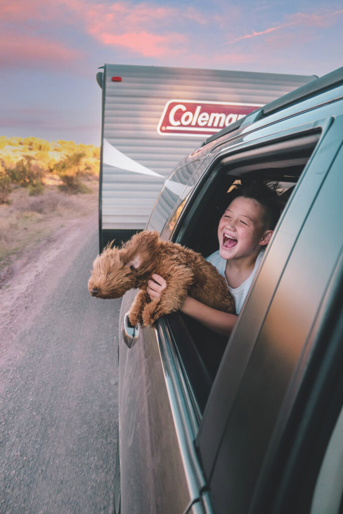 a boy and his dog leaning out the window in front of a trailer