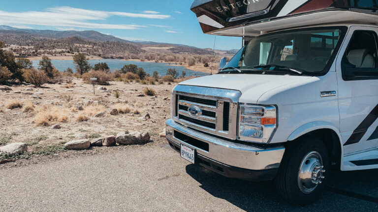 a Class C camper next to a lake
