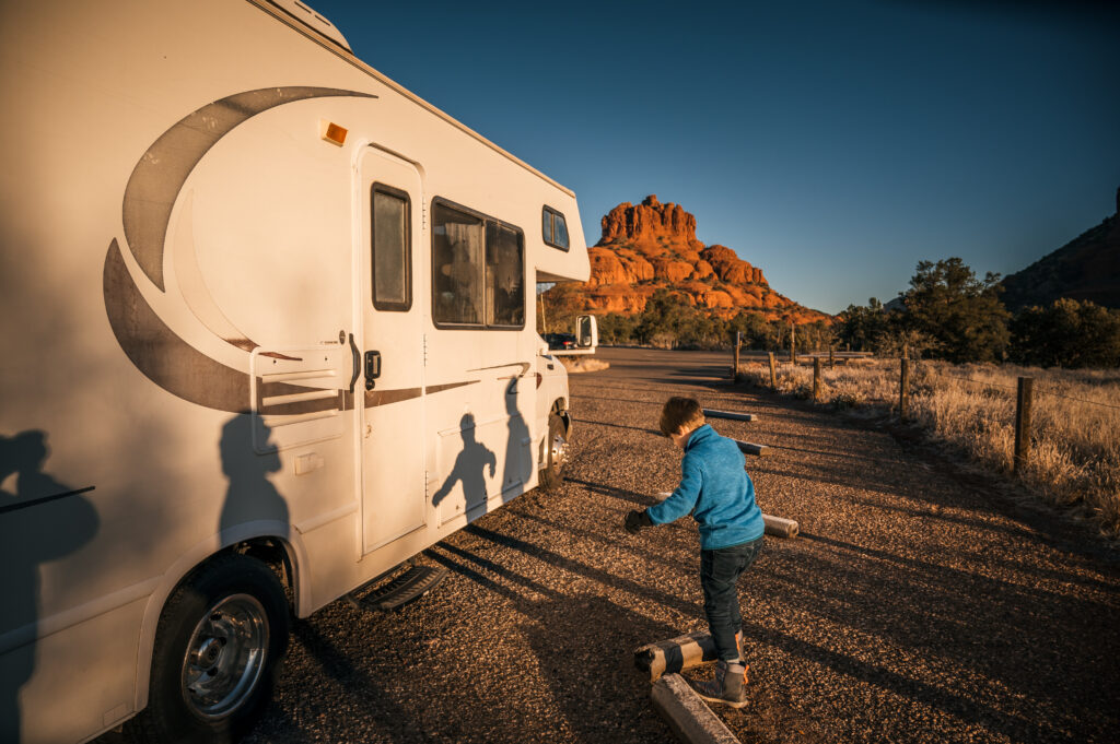 a kid next to an RV at sunset