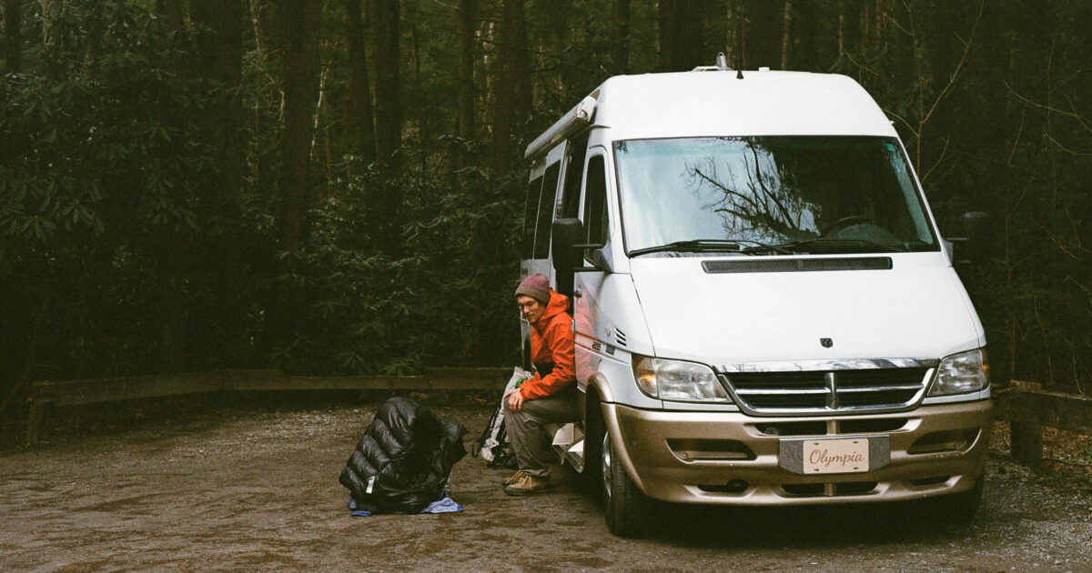 man sitting in the doorway of a class b campervan