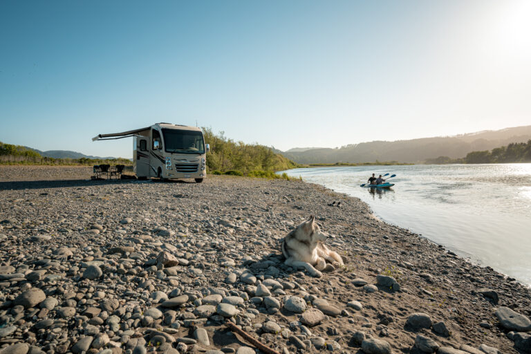 an RV set up by a river with kayakers