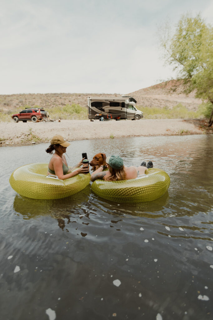 people floating in innertubes with an RV in the background