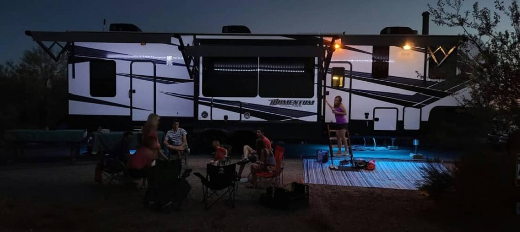 A toy hauler set up at a campsite with a family gathered around the front