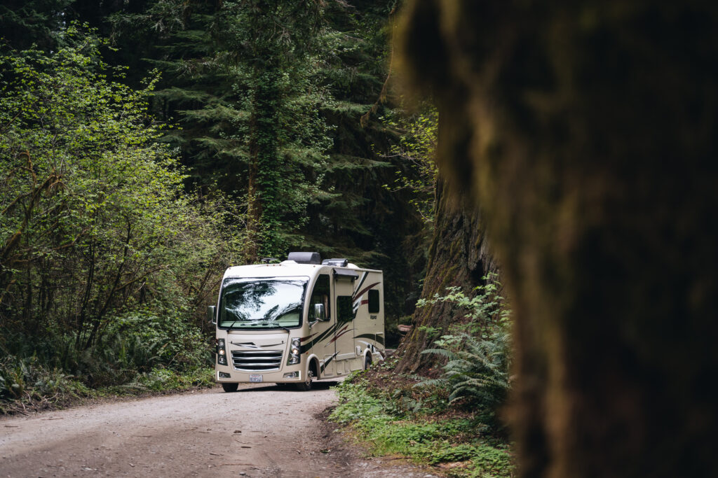 a Class A RV driving through the forest