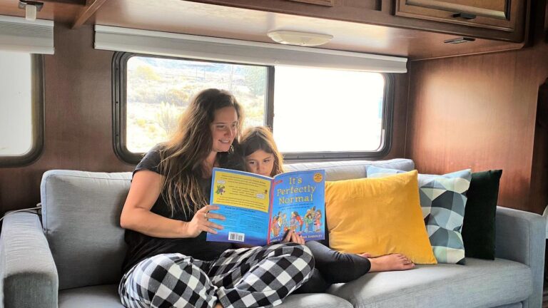 a woman reading a book to a child on an RV couch