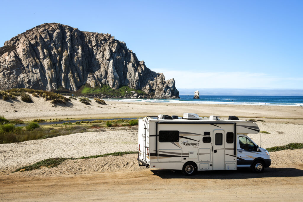 a Class C RV parked by the beach