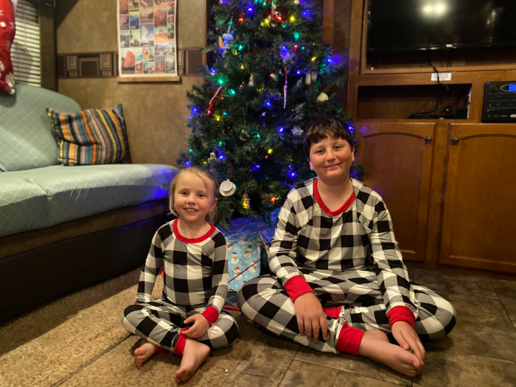 My kids sitting in front of our Christmas tree in our RV. 