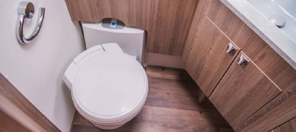 an RV toilet installation in a motorhome bathroom with wood paneling