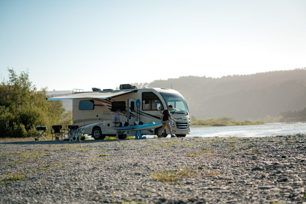 a Class A motorhome next to a lake