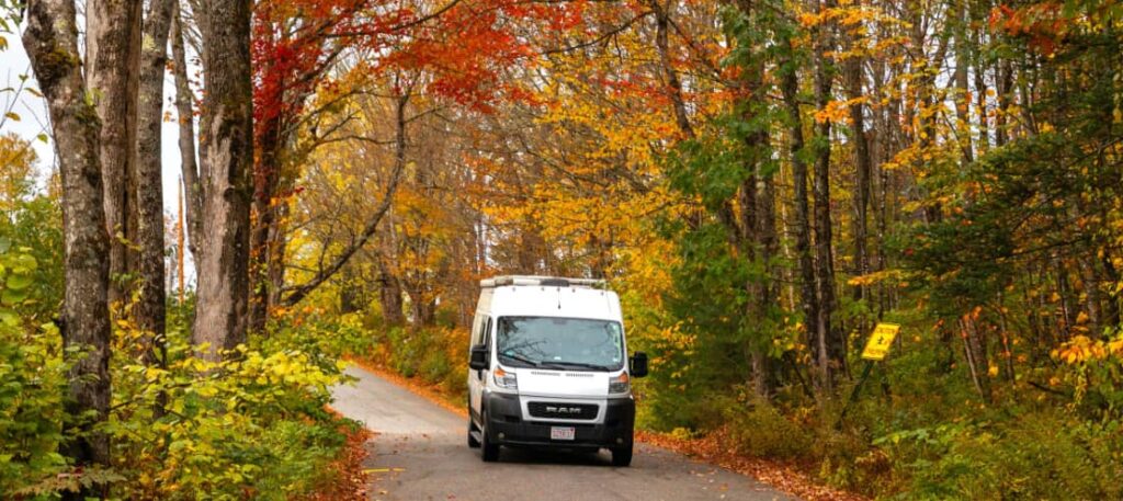 a campervan traveling through fall foliage for November travel