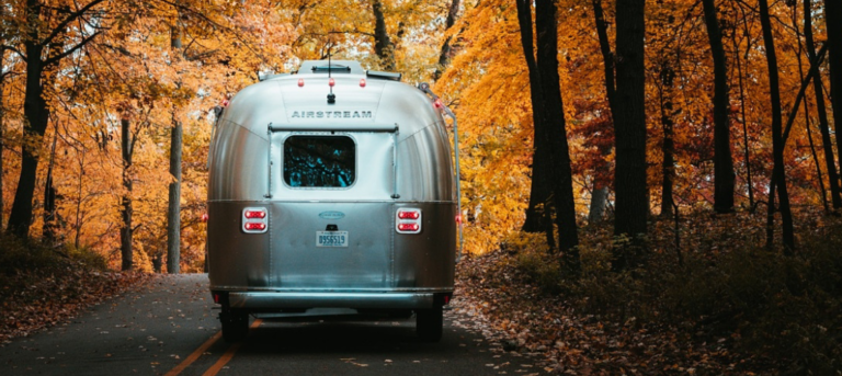 an airstream trailer in the woods surrounded by fall colors