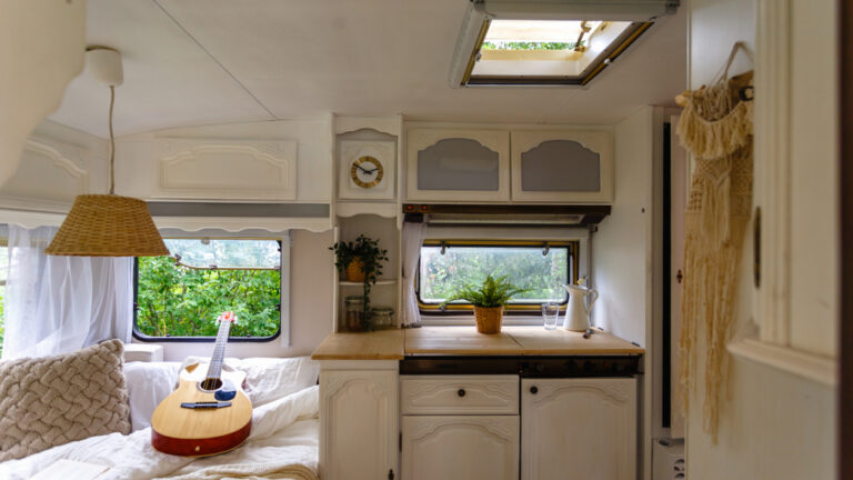 Inside a small RV - guitar rests on a bed next to a small kitchenette
