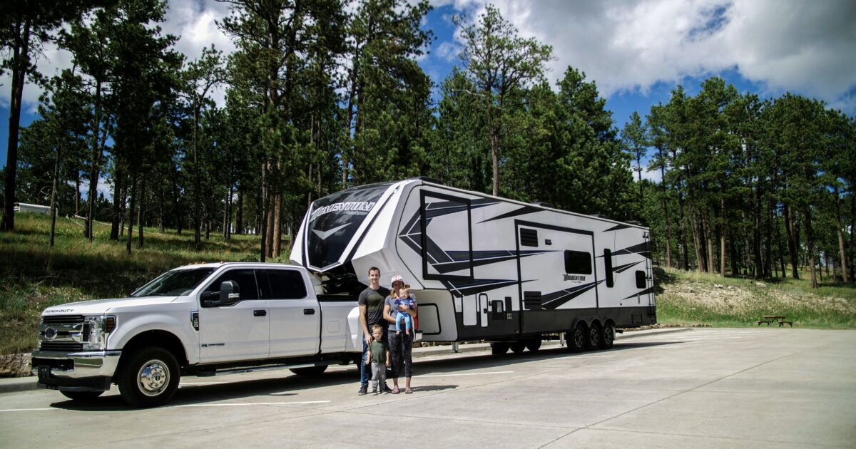 Family in front of fifth wheel after after buying an RV