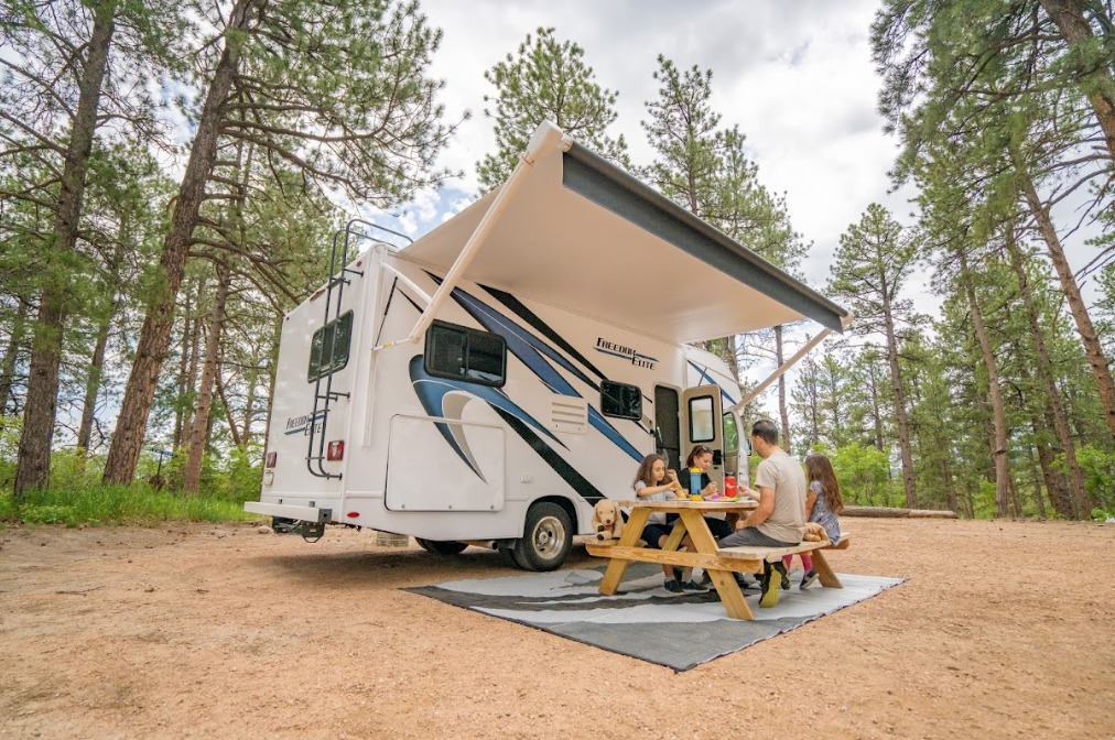 a family picnicking in front of a Class C camper