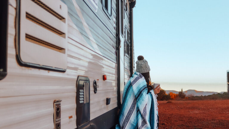 a woman outside an RV watching the sunrise