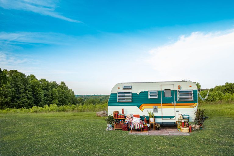 Small travel trailer parked in the middle of a field on a clear day