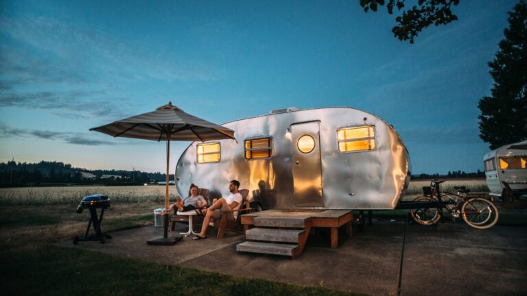 Couple sitting outside a teardrop trailer at twilight