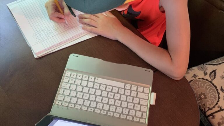 Boy slouches over notebook and laptop