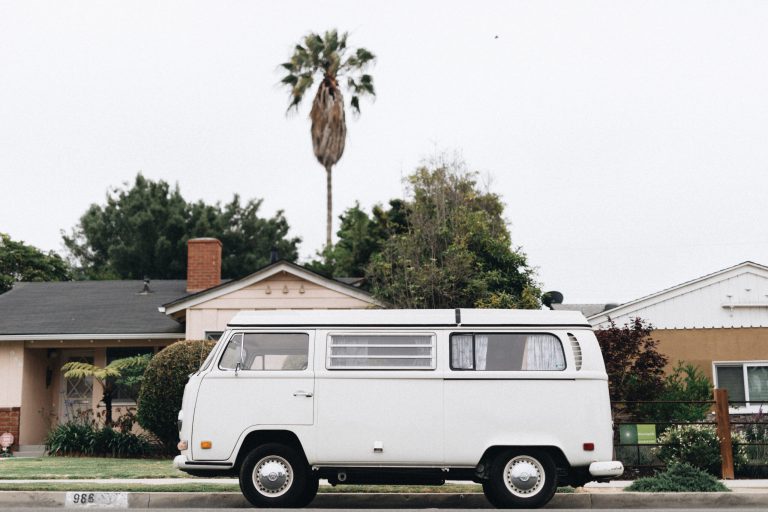 VW bus RV parked in front of house next to palm tree