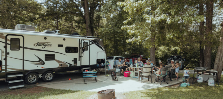 travel trailer with family camping next to it