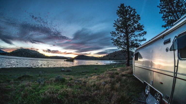 an Airstream trailer at sunset next to a lake
