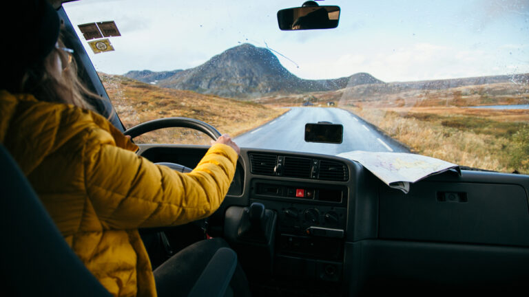 Female traveller drive old vintage camper van on empty winter road
