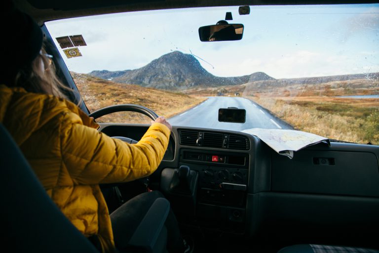 Female traveller drive old vintage camper van on empty winter road