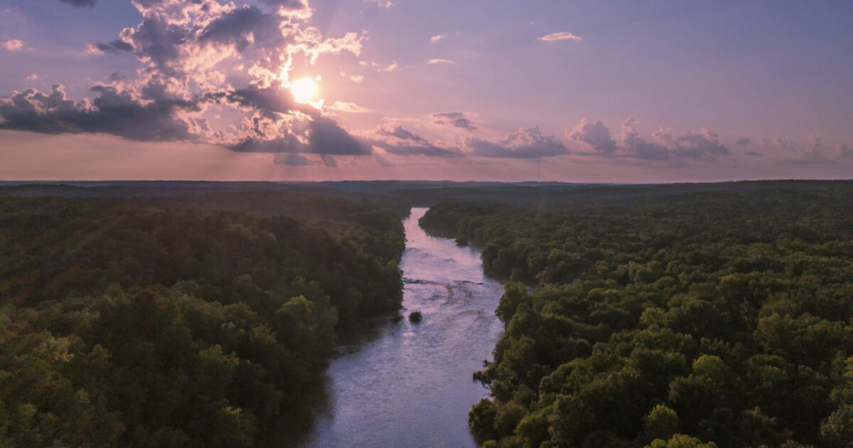 River running through a forest against a blue and pink sky, something you might see while North Carolina boondocking