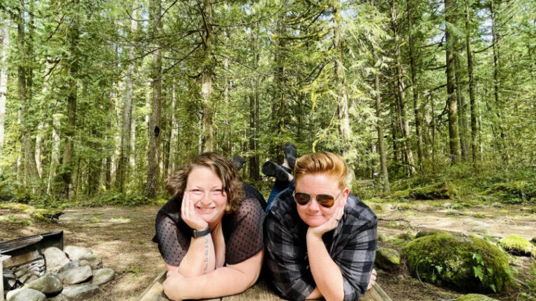 Women pose on a picnic table and smile
