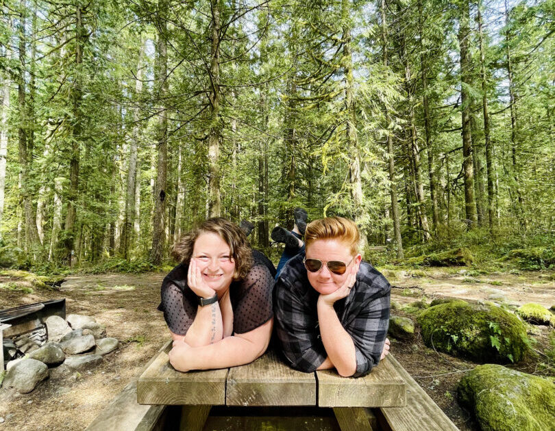 Women pose on a picnic table and smile