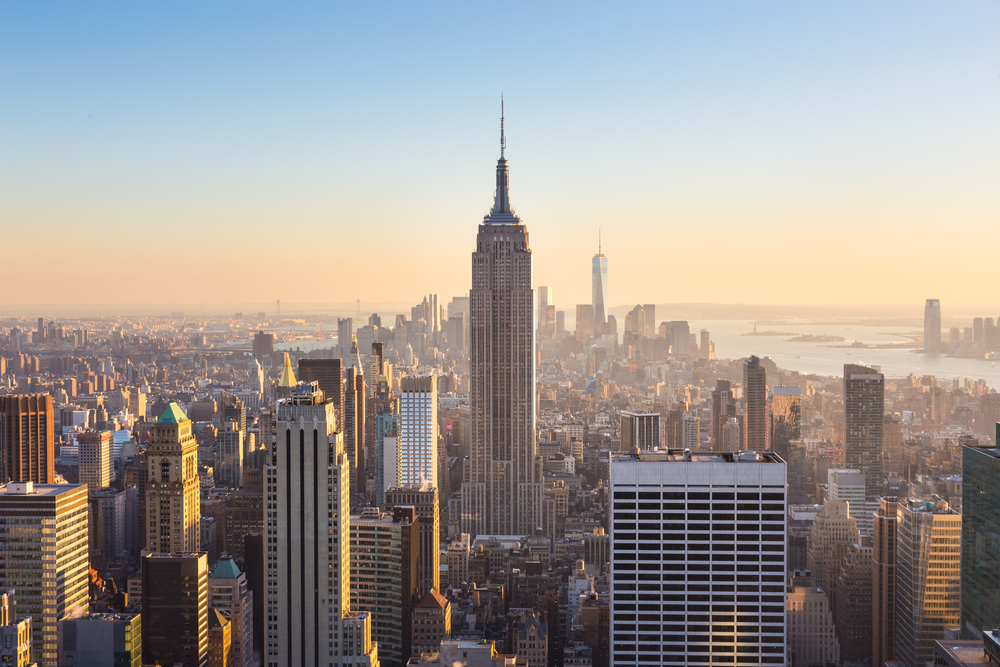 New York City. Manhattan downtown skyline with illuminated Empire State Building and skyscrapers at sunset.