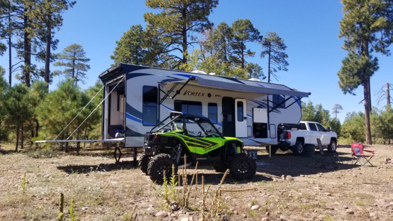 rv with four wheeler parked next to it