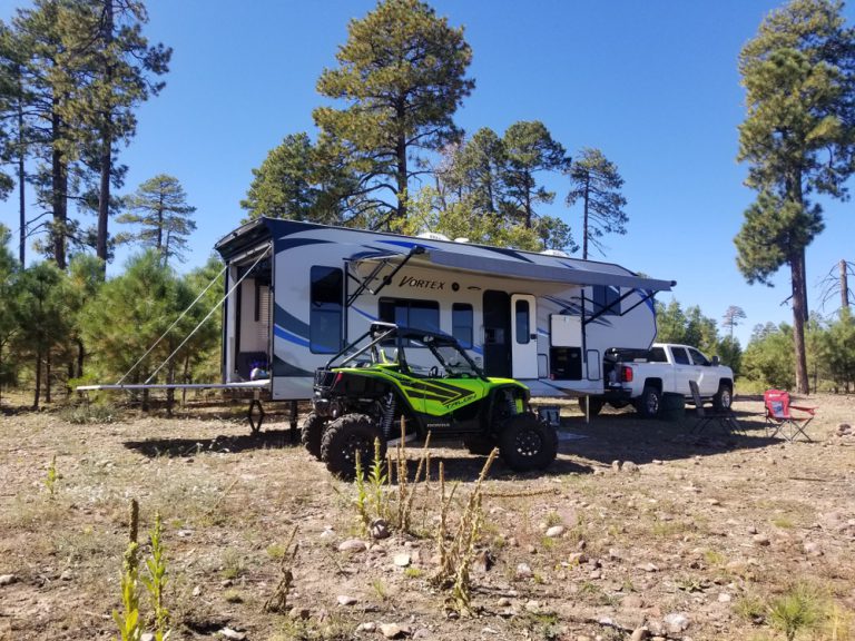 rv with four wheeler parked next to it