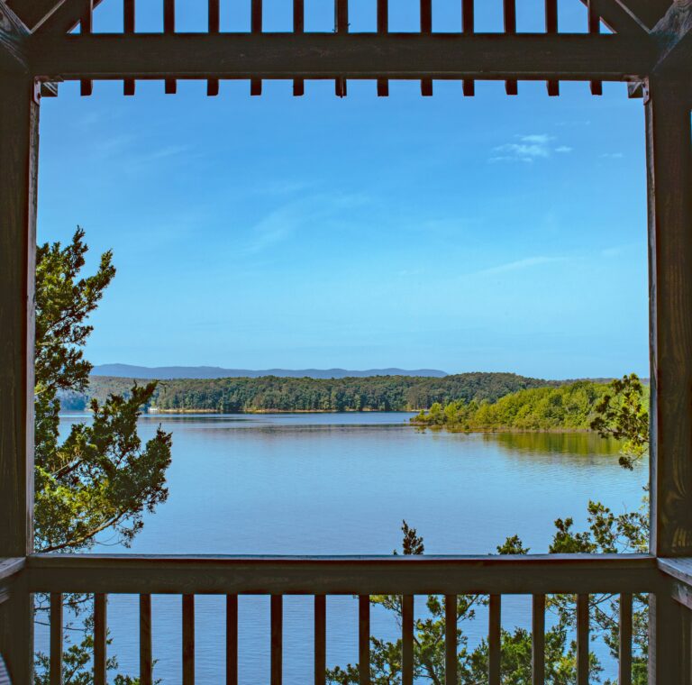 Clear blue lake with trees and hills in the background under a blue sky