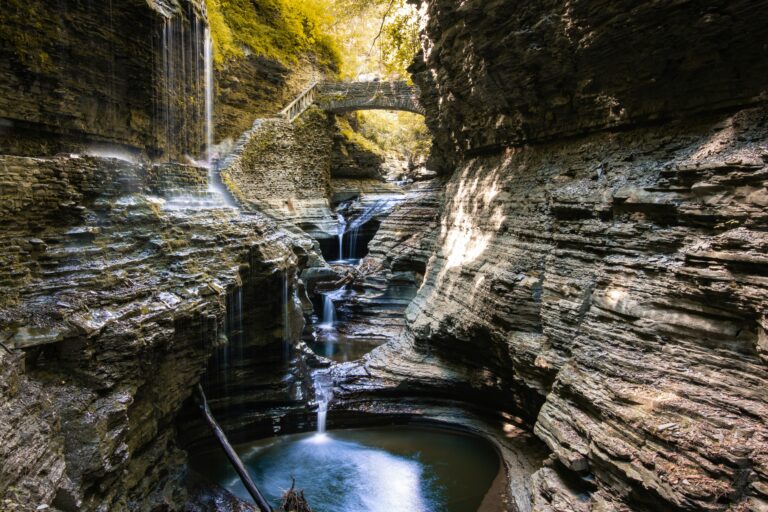 A waterfall dripping down from steep gray rocks during the daytime