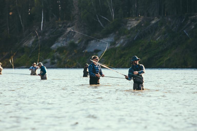 A group of men wading in a river and fly-fishing.