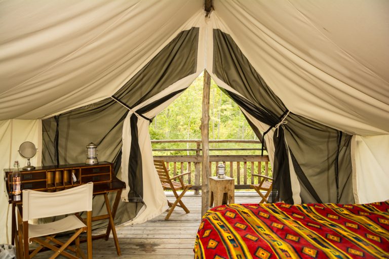 The inside of an elaborate tent with a bright blanket and unique desk under a canopy.