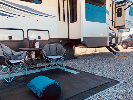 Yoga mat and chairs set up outside a fifth-wheel trailer
