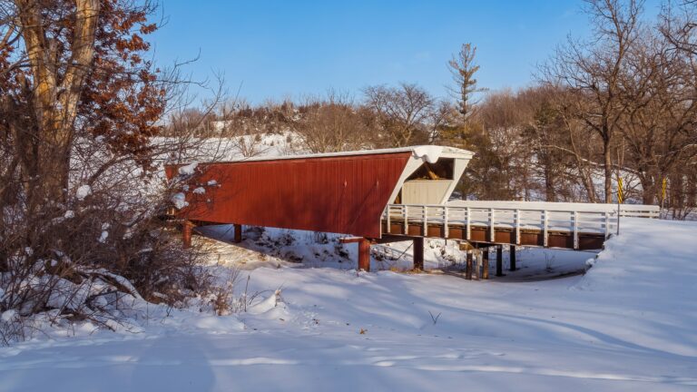 A red bridge stretching over a snowy embankment.