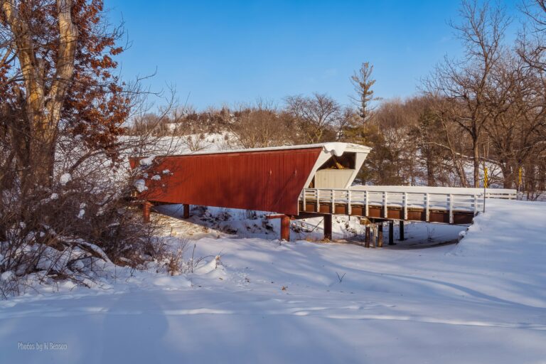 A red bridge stretching over a snowy embankment.