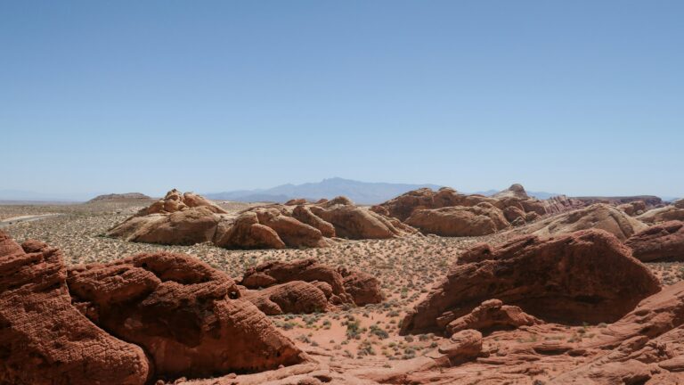 A stretch of desert landscape dotted with orange rock formations under a clear blue sky.