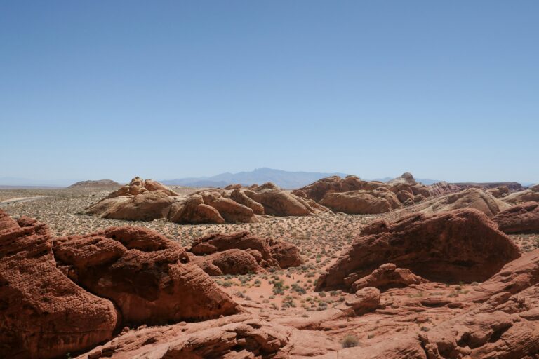 A stretch of desert landscape dotted with orange rock formations under a clear blue sky.