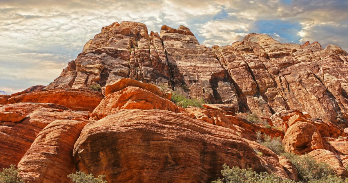 Red rock cliffs sitting under high whispy clouds in a blue sky