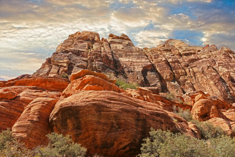 Red rock cliffs sitting under high whispy clouds in a blue sky